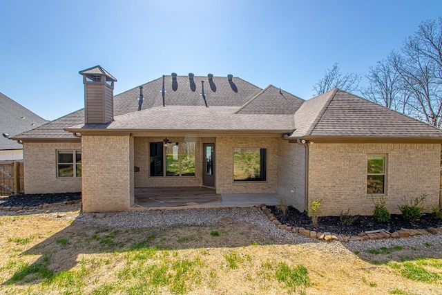 back of property featuring brick siding, a patio area, fence, and roof with shingles