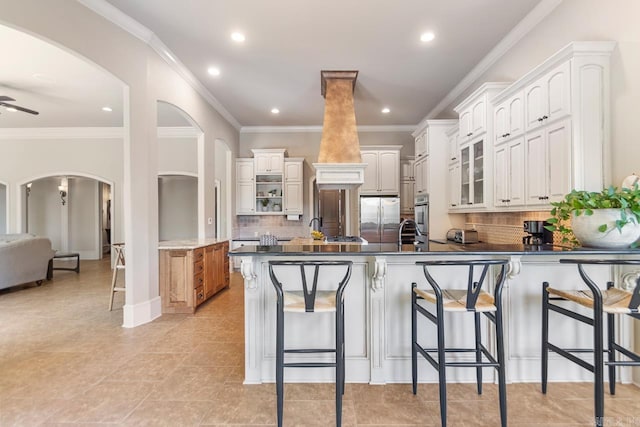 10 Lakewood Park Dr, North Little Rock, AR 72116 - kitchen featuring a breakfast bar, stainless steel refrigerator, arched walkways, a peninsula, and backsplash