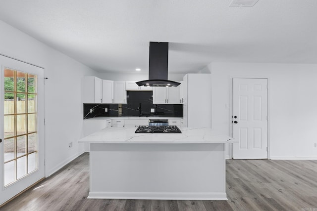 300 Dryad Ln, Little Rock, AR 72205 - kitchen featuring baseboards, white cabinets, island exhaust hood, light wood finished floors, and backsplash