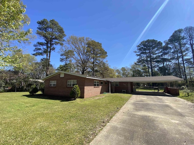 ranch-style home featuring a front lawn, brick siding, concrete driveway, and an attached carport