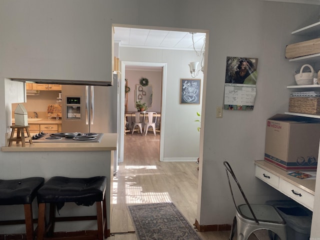 kitchen with stainless steel appliances, light wood-type flooring, a kitchen breakfast bar, and light countertops