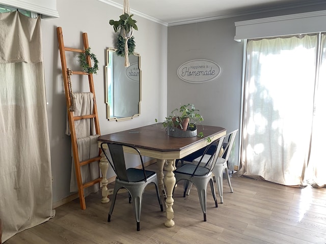 dining area with light wood-style floors and crown molding