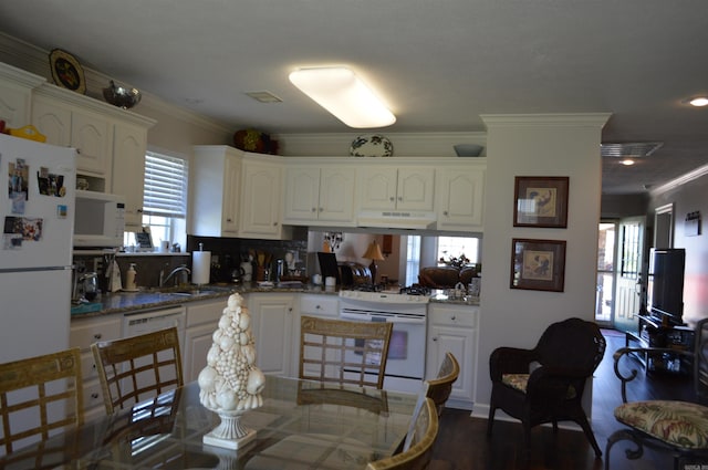 kitchen featuring white appliances, white cabinetry, under cabinet range hood, and a healthy amount of sunlight