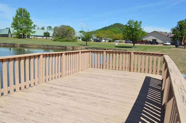wooden terrace featuring a lawn and a water view