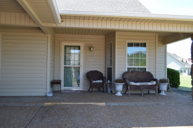 doorway to property featuring a shingled roof and covered porch