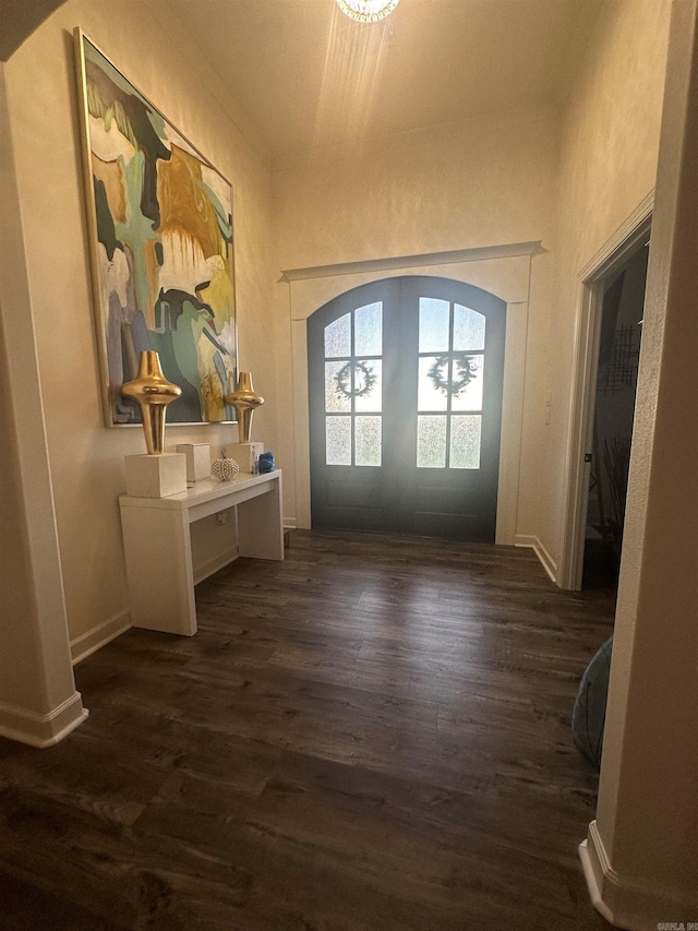 entryway featuring arched walkways, baseboards, french doors, and dark wood-type flooring