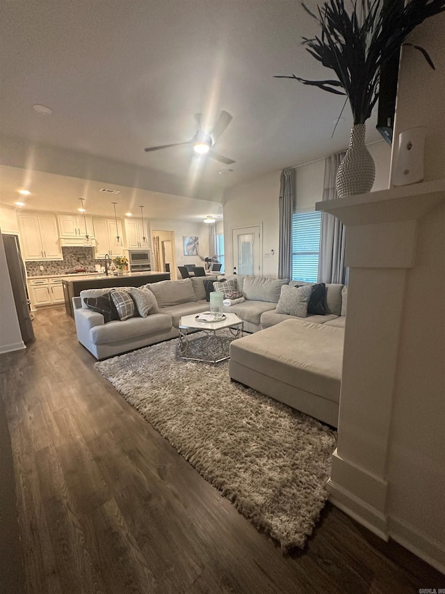 living area with a ceiling fan and dark wood-style floors