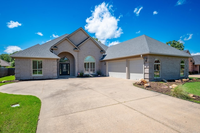 view of front of house featuring fence, roof with shingles, brick siding, a garage, and concrete driveway
