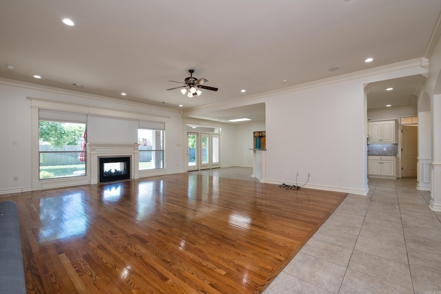 unfurnished living room with crown molding, recessed lighting, ceiling fan, and a glass covered fireplace