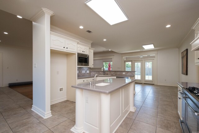 kitchen with crown molding, a sink, backsplash, light tile patterned floors, and stainless steel appliances