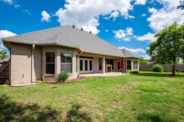 rear view of property with a lawn, a shingled roof, a fenced backyard, and a patio area