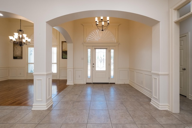 entryway with arched walkways, a notable chandelier, a decorative wall, and a wealth of natural light