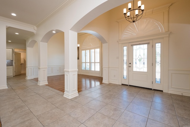 entrance foyer featuring a chandelier, a decorative wall, and light tile patterned flooring