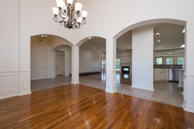 unfurnished dining area with a chandelier, a glass covered fireplace, wood finished floors, and a decorative wall