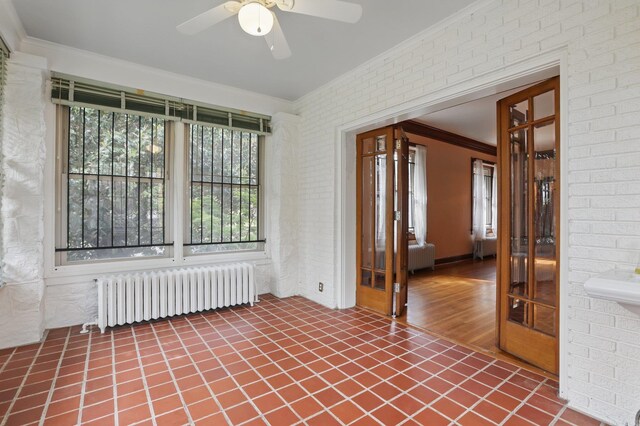 empty room featuring crown molding, a ceiling fan, and radiator heating unit