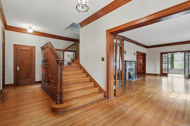 stairs featuring baseboards, ornamental molding, wood finished floors, and a chandelier