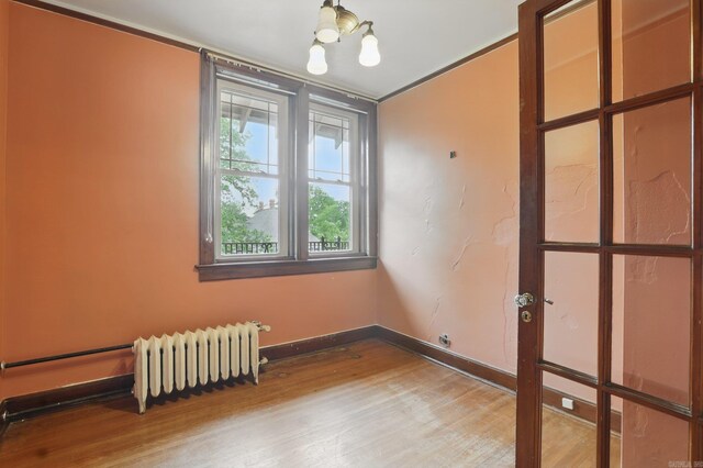 spare room with radiator heating unit, baseboards, and wood finished floors