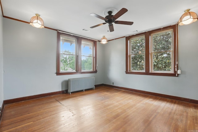 spare room featuring visible vents, radiator heating unit, a wealth of natural light, and light wood-type flooring