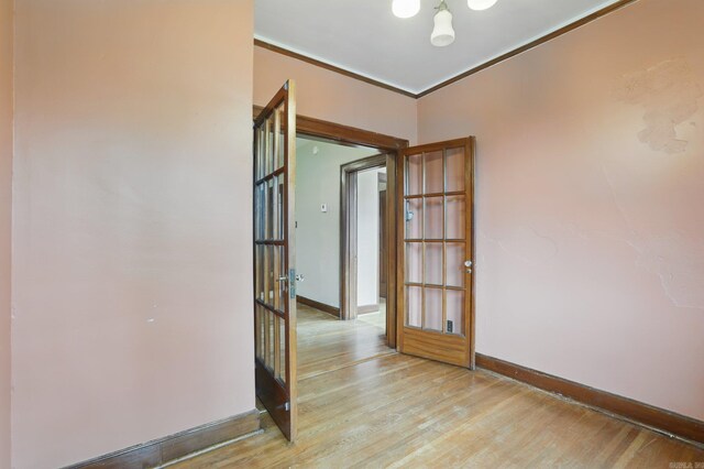 unfurnished room with baseboards, ornamental molding, and light wood finished floors
