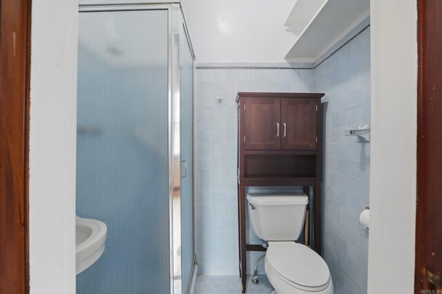 full bathroom featuring toilet, tile walls, and a stall shower
