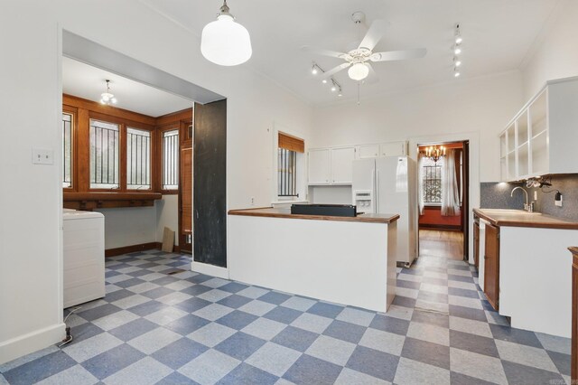kitchen with ceiling fan, white refrigerator with ice dispenser, a sink, track lighting, and white cabinets