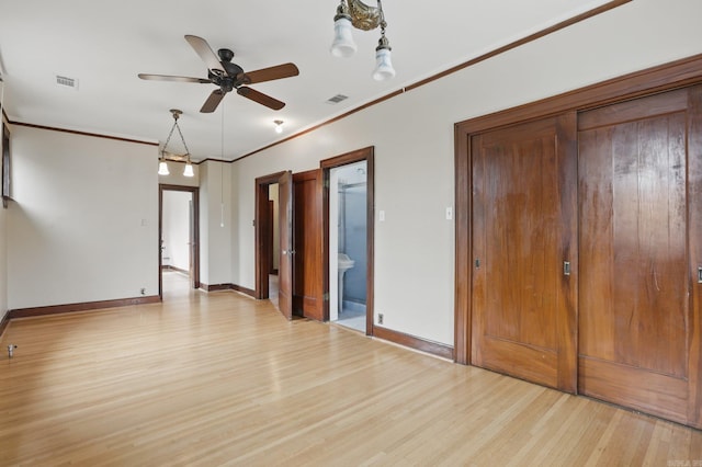 empty room with ceiling fan, visible vents, baseboards, light wood finished floors, and ornamental molding