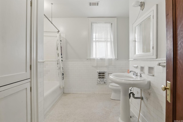 full bath featuring toilet, shower / bath combo with shower curtain, a wainscoted wall, heating unit, and visible vents