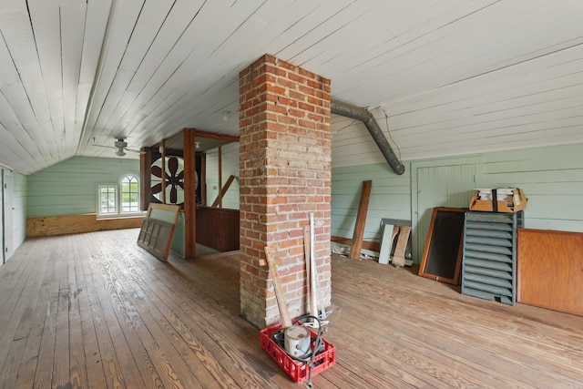additional living space featuring vaulted ceiling, wooden walls, and hardwood / wood-style floors