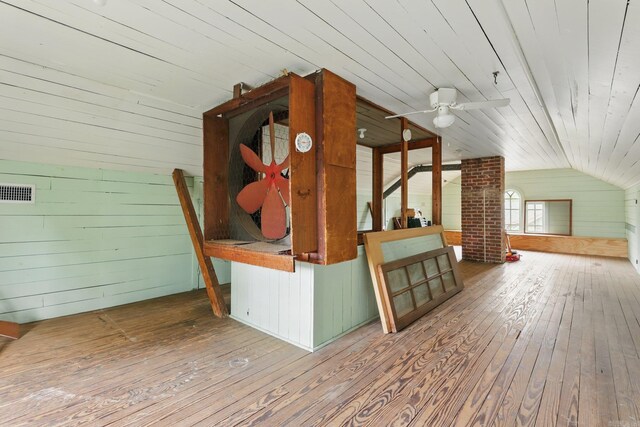 additional living space featuring wooden walls, a ceiling fan, hardwood / wood-style flooring, and lofted ceiling