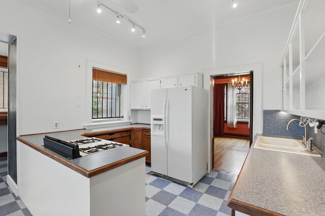 kitchen featuring crown molding, light floors, a sink, cooktop, and white fridge with ice dispenser