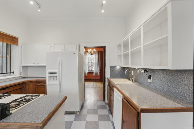 kitchen with crown molding, white appliances, light floors, rail lighting, and a sink