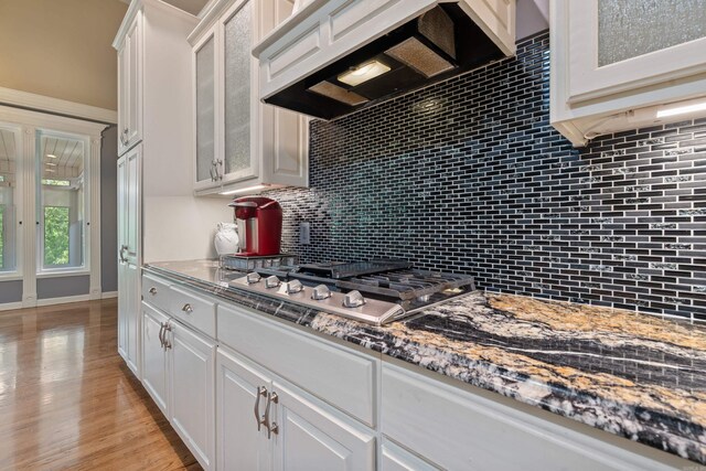 kitchen featuring glass insert cabinets, white cabinets, tasteful backsplash, and stainless steel gas stovetop