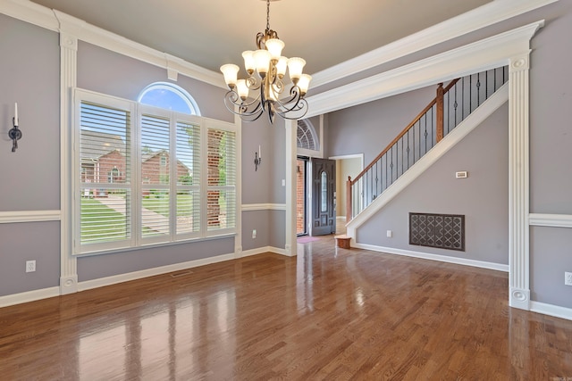 unfurnished dining area featuring an inviting chandelier, baseboards, crown molding, and wood finished floors
