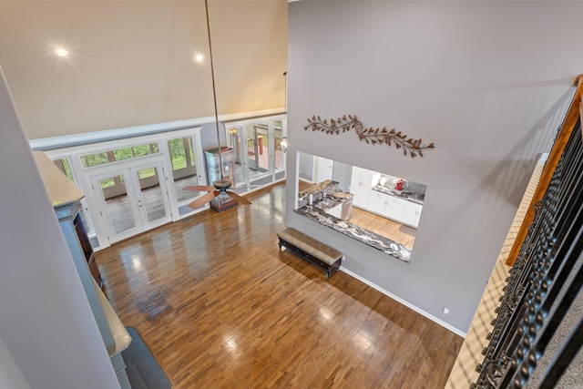 living room with french doors, a high ceiling, wood finished floors, and stairway