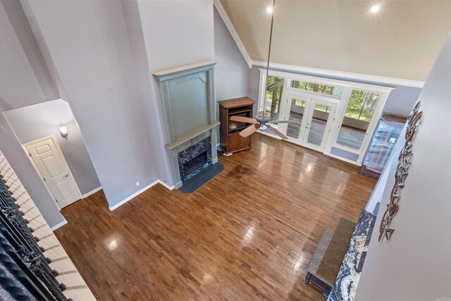 unfurnished living room with high vaulted ceiling, french doors, baseboards, wood finished floors, and a tile fireplace