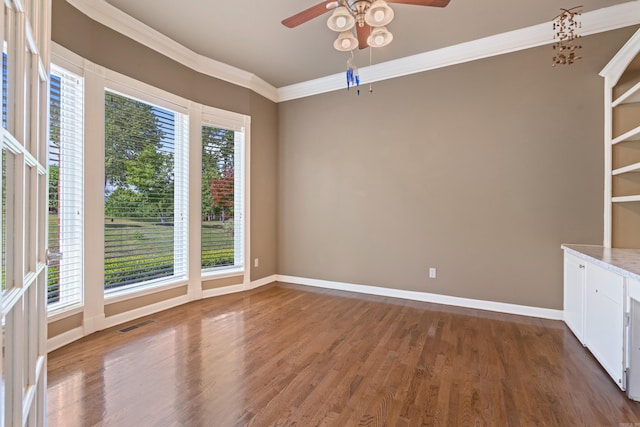 spare room featuring visible vents, ornamental molding, ceiling fan, and wood finished floors
