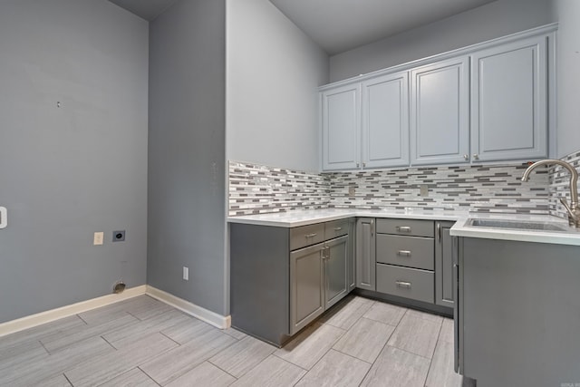 clothes washing area with cabinet space, a sink, electric dryer hookup, baseboards, and wood tiled floor