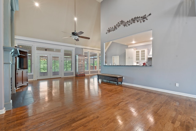 unfurnished living room featuring baseboards, a high ceiling, a ceiling fan, and wood finished floors