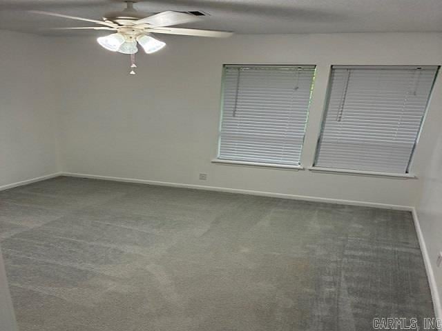 carpeted spare room featuring baseboards and ceiling fan