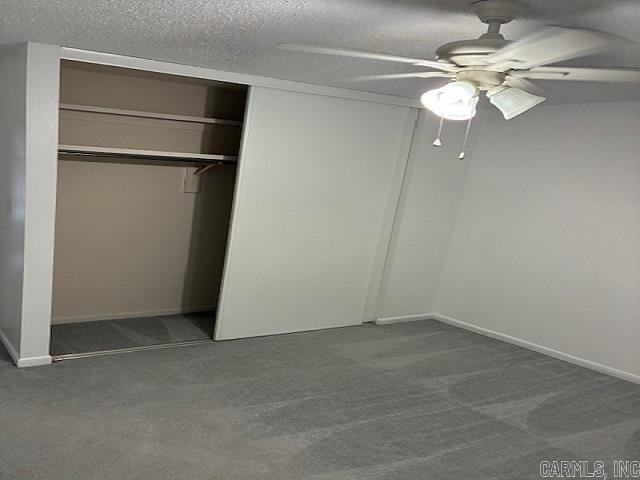 unfurnished bedroom featuring ceiling fan, a textured ceiling, baseboards, a closet, and dark colored carpet
