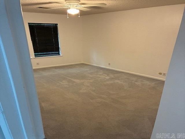 spare room featuring carpet floors, baseboards, a ceiling fan, and a textured ceiling