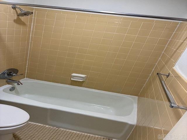 bathroom featuring toilet, washtub / shower combination, and tile patterned flooring