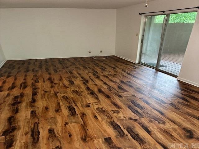 spare room featuring baseboards and dark wood-style flooring