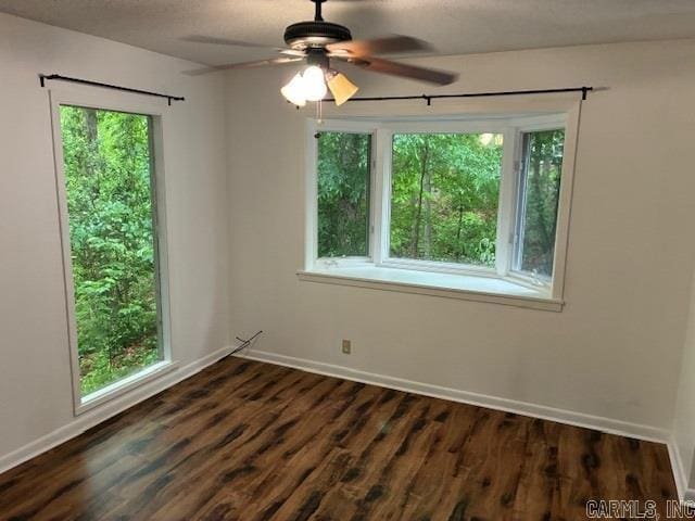 unfurnished room featuring dark wood-style flooring, baseboards, and ceiling fan