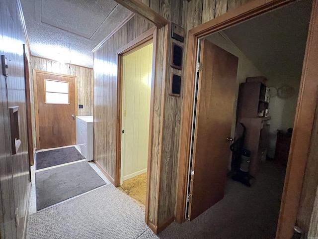 corridor with washer / dryer, carpet floors, wooden walls, and a textured ceiling