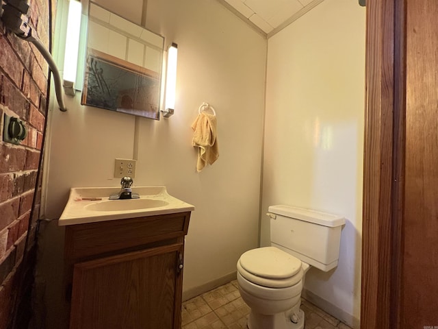 half bath featuring vanity, baseboards, toilet, and lofted ceiling