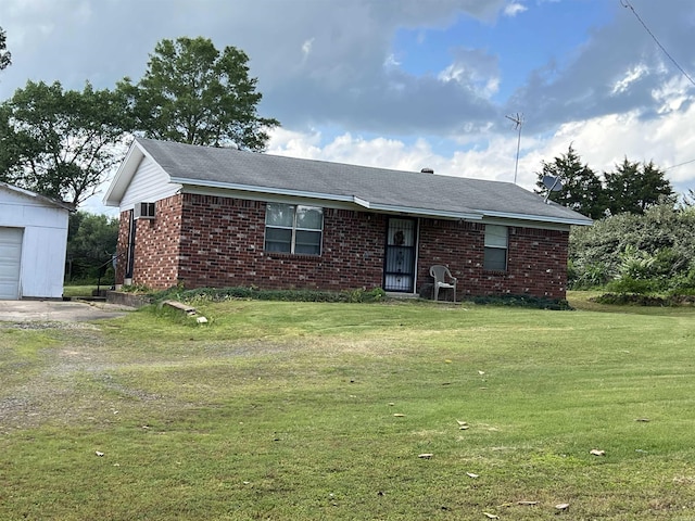ranch-style house with brick siding, a garage, an outbuilding, and a front lawn