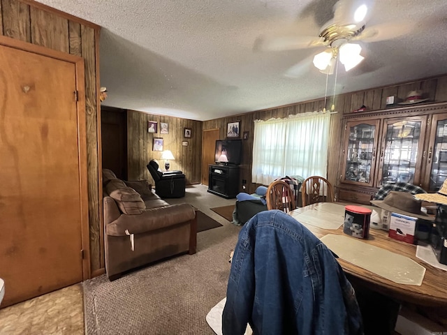 dining room featuring wooden walls, a textured ceiling, ceiling fan, and a wood stove