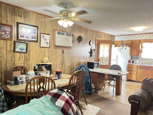 dining room featuring crown molding, ceiling fan, a wall unit AC, and wood walls