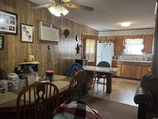 dining area with an AC wall unit, a ceiling fan, a textured ceiling, and wooden walls
